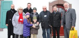 Sieben menschen und zwei Kinder im Winter vor einem Schloss
