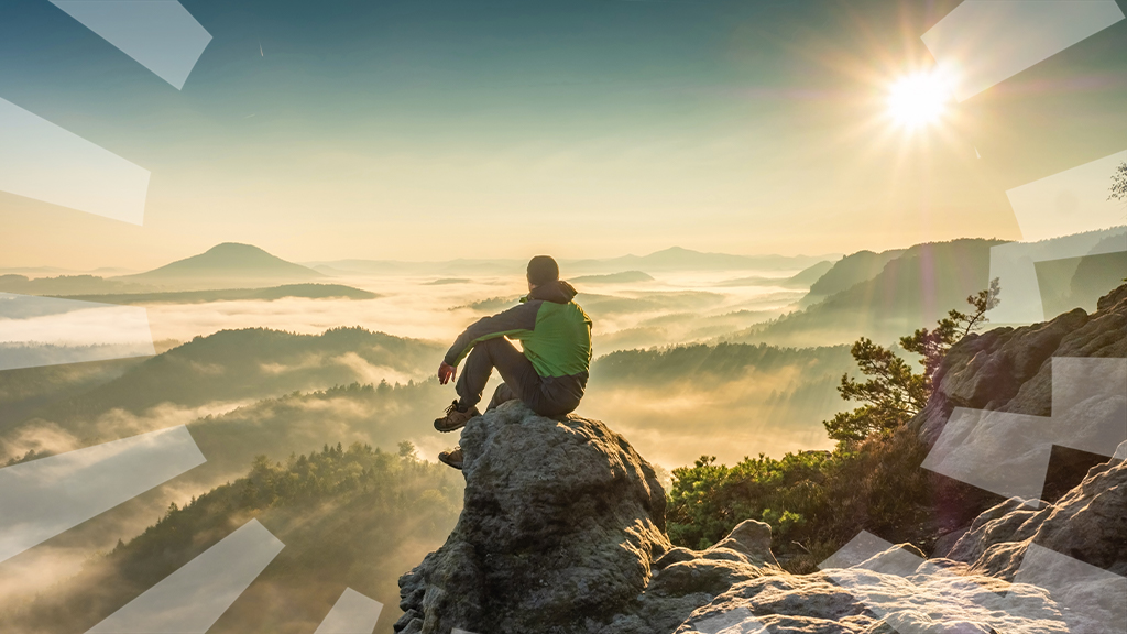 Ein Mann sitzt auf einem Stein und blick ins Tal 